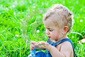 Baby boy sitting on green grass in park