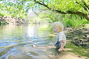 Baby Boy Sitting in Muddy River in Forest