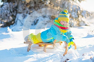 Baby boy on sled. Child sledding. Kid with sledge