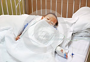 Baby boy sleeping with attaching intravenous tube to hand on bed at hospital. Baby admitted at hospital. Kid patients have IV tube photo