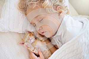 Baby boy sleeping with kitten. Child and cat