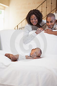 Baby boy sleeping peacefully on couch watched by parents