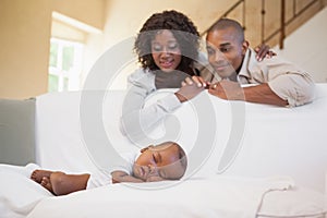 Baby boy sleeping peacefully on couch watched by parents