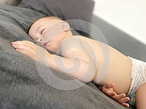 A baby boy sleeps soundly on his stomach during the day on a gray blanket photo