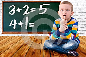 Baby boy solve mathematics examples.The student thinks and feels near the Board.Mathematical tasks .