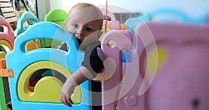 Baby boy standing in colorful playpen