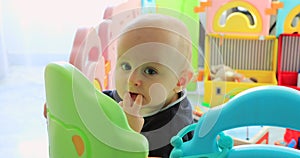 Baby boy standing in colorful playpen