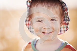 Baby boy standing in grass on the fieald with dandelions