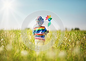 Baby boy standing in grass on the fieald with dandelions