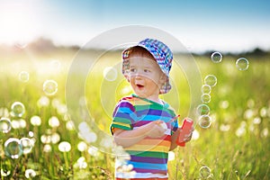 Baby boy standing in grass on the fieald with dandelions