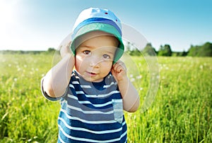 Baby boy standing in grass on the fieald with dandelions