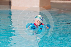 Baby boy swims independently in the pool.