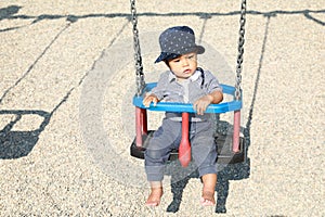 Baby boy on a swing on kids playground