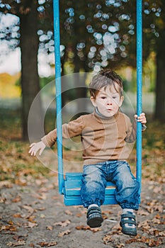 Baby boy swinging in autumn park