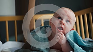 Baby boy toddler crawling in crib at kids nursery room at home. looking and smiling at the camera