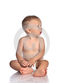 Baby boy toddler in diaper sits on the floor with head turned and looks aside