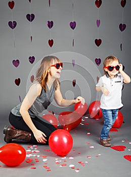 Baby boy toddler with mother in studio wearing funny glasses smiling laughing having fun