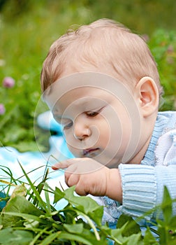 Baby boy touching grass and thinking