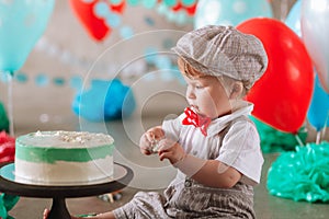 Baby boy touching his first birthday cake. Making messy cakesmash in decorated studio location