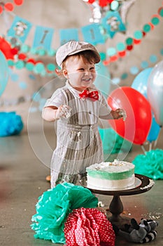 Baby boy touching his first birthday cake. Making messy cakesmash in decorated studio location