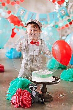 Baby boy touching his first birthday cake. Making messy cakesmash in decorated studio location