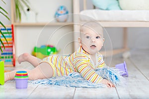 Baby boy among the toys in the children`s room, cute funny smiling little baby playing on the floor, the concept of children`s