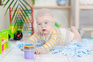 Baby boy among the toys in the children`s room, cute funny smiling little baby playing on the floor, the concept of children`s