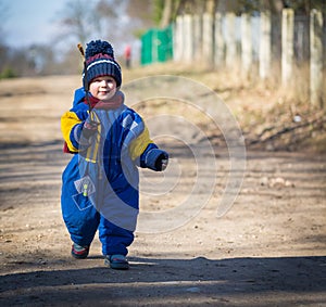 Baby boy walking by sandy rural road