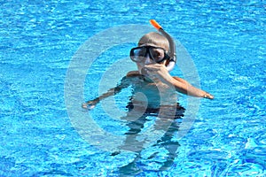 Baby boy in the water mask in the pool. Child swimmer in the water autdoor.