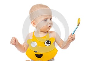 Baby boy in yellow bib with a spoon. Portrait of a baby with a dirty face. isolated on white