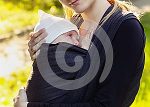 Baby on the breast of the mother. Newborn woven wrap babywearing