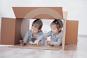 Baby brother and child sister playing in cardboard boxes in nursery