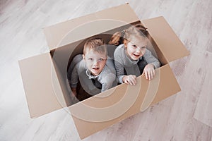 Baby brother and child sister playing in cardboard boxes in nursery