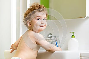 Baby brushing teeth in bathroom photo