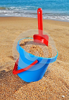 Baby bucket with sand and a shovel on the beach