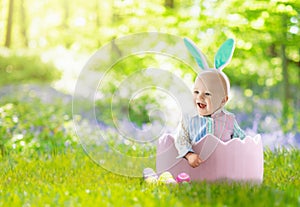 Baby with bunny ears on garden Easter egg hunt
