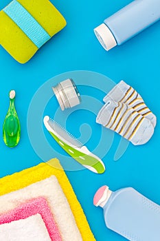 Baby care. Bath cosmetics and accessories for child. Shampoo, gel, cream, towel, brush on blue background top view