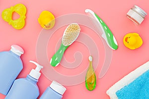 Baby care. Bath cosmetics and accessories for child. Shampoo, gel, cream, yellow rubber duck on pink background top view