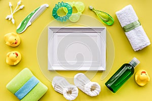 Baby care with bath set, frame, ducklings and towel on yellow background top view mockup