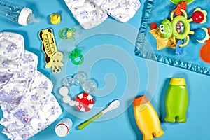 Baby care with bath set. Nipple, toy, diapers, shampoo on blue background top view mockup