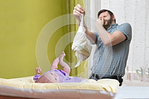 Baby care concept. Father od dad is changing stinky diaper photo