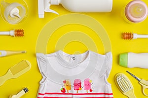Baby care kit and clothing on yellow background