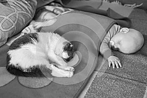 Baby and cat sleep together in the bed, black and white photo