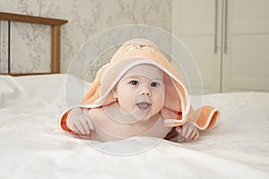 Baby Caucasian girl boy 5 months crawls out under towel, cheerful laughing open mouth, soft focus