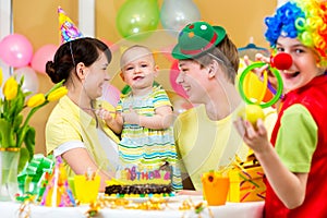 Baby celebrating first birthday with parents and clown