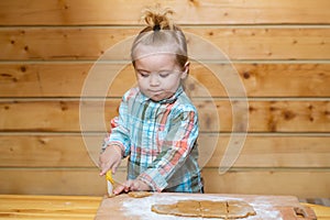 Baby child boy cooking, playing with flour at wooden kitchen.