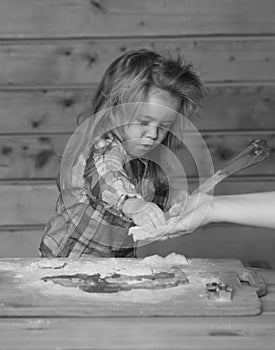 Baby child cooking, playing with flour at wooden kitchen.