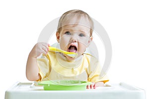 Baby child eating healthy food with a spoon
