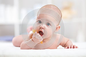 Baby child lying on belly weared with teether in mouth