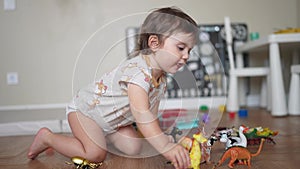 Baby child playing toys animals on the floor in kindergarten. Happy family kid concept. Baby play toys animals scattered